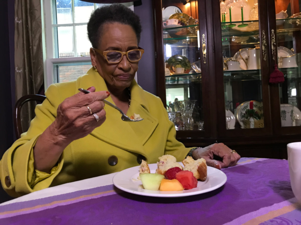 Senior woman sitting at dining room table eating healthy meal.