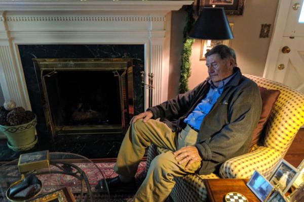 Senior man sits alone in chair in his living room