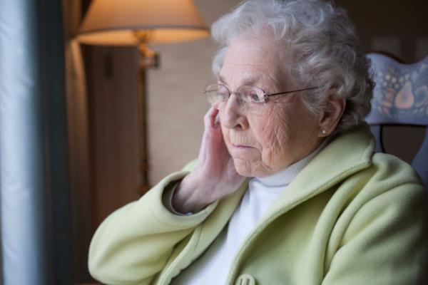 Senior woman with Alzheimer's sitting in chair at home.
