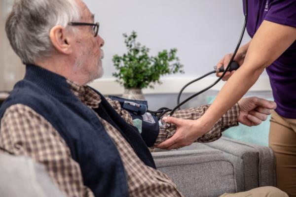 Home Instead Caregiver taking blood pressure reading for senior man at home