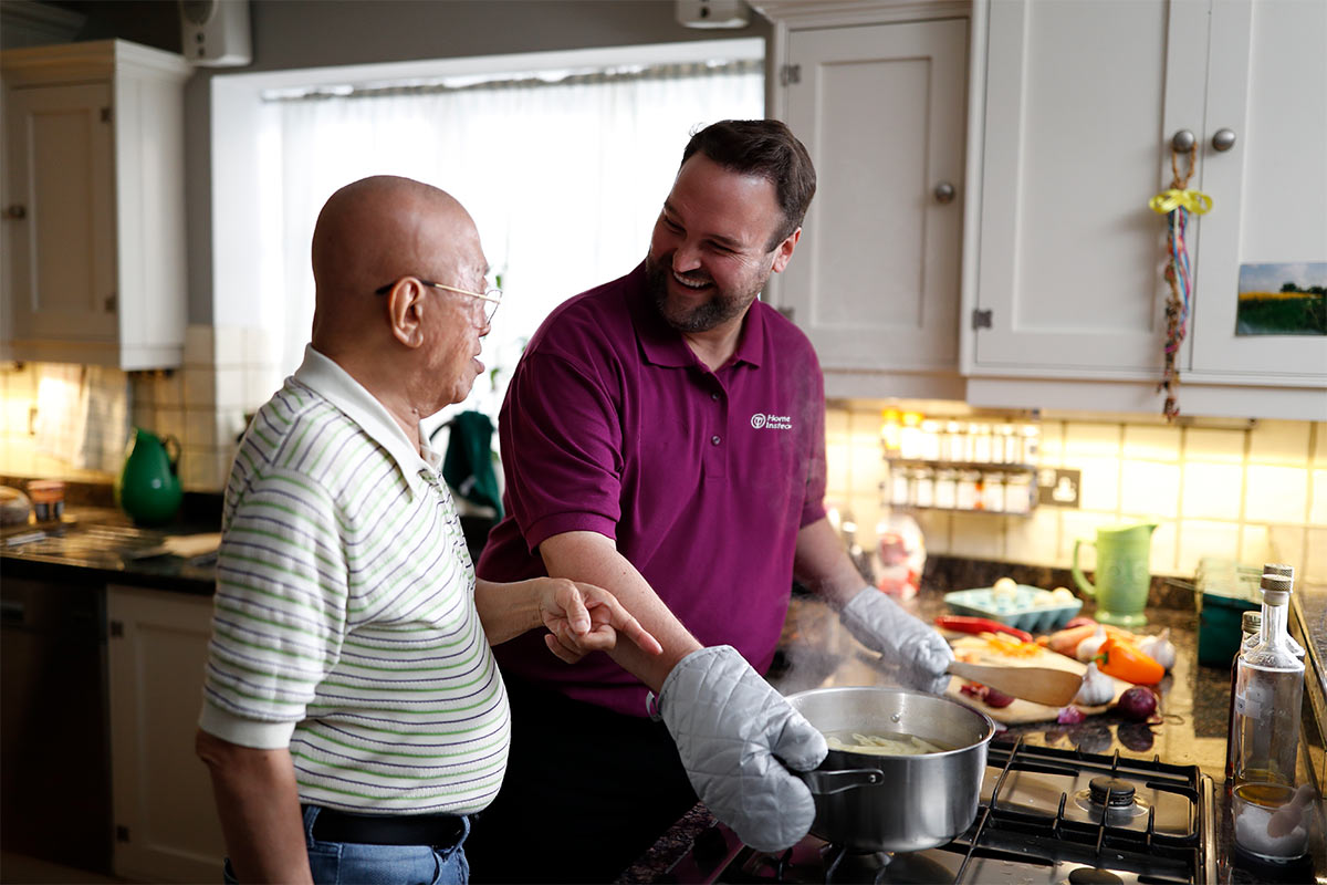 Care Professional helping senior cook in the kitchen
