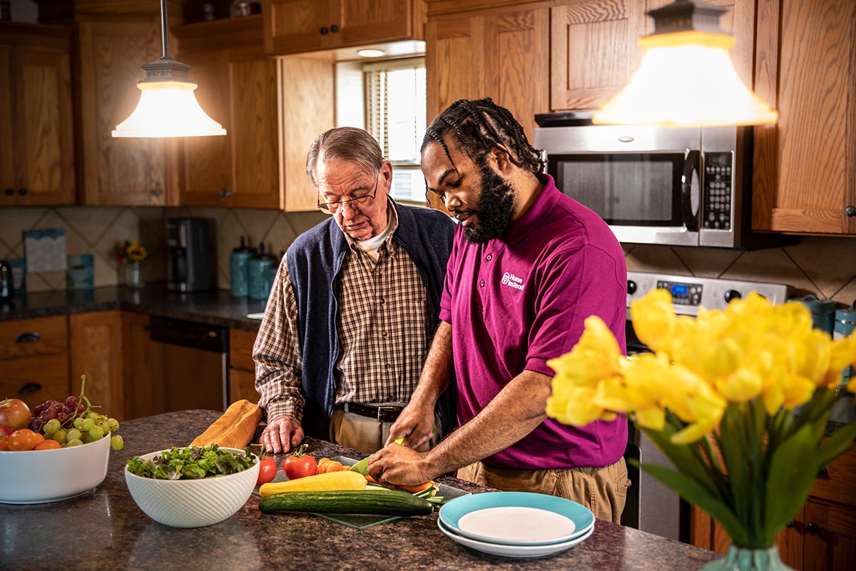 Home Instead Caregiver and senior man prepare a healthy meal together in kitchen
