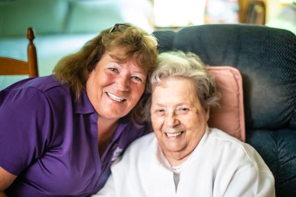 Caregiver smiling with her senior client in her home.