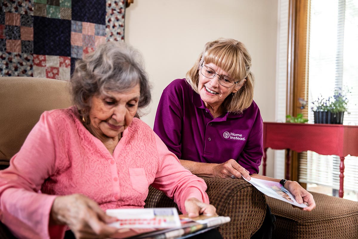 Home Instead Caregiver and senior woman sort through mail together at home
