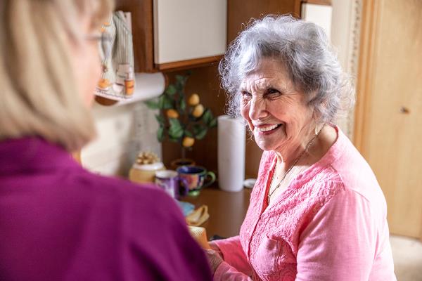 Senior woman smiling while standing in kitchen at home