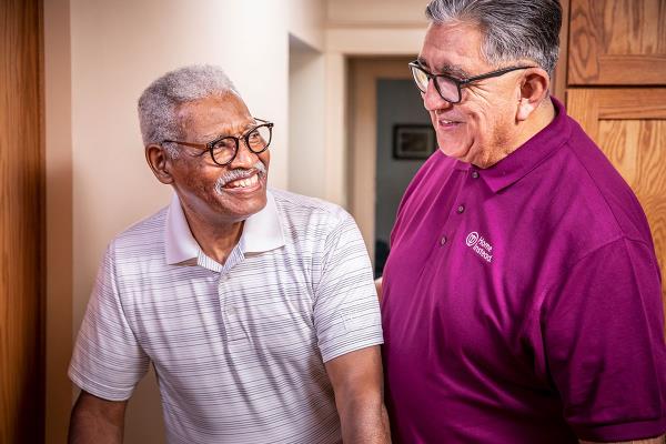 Home Instead Caregiver helps senior man walking at home