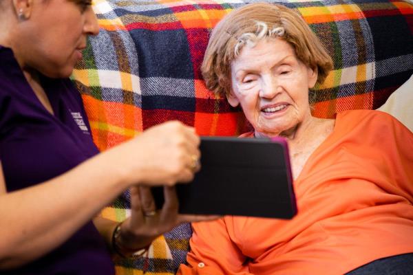 Home Instead Caregiver helps senior woman on video call with family