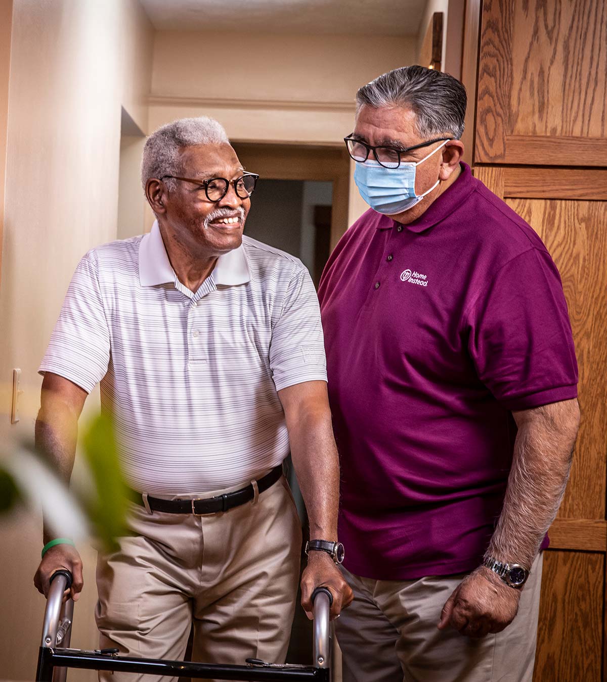 Home Instead Caregiver helps senior man with walker at home in our home care service area