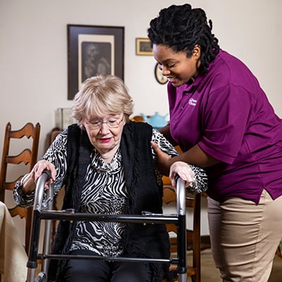 Home Instead Caregiver helps senior woman using walker at home