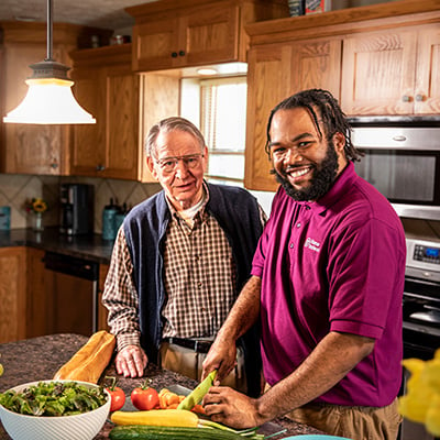 Home Instead Caregiver and senior man cooking together in kitchen at home