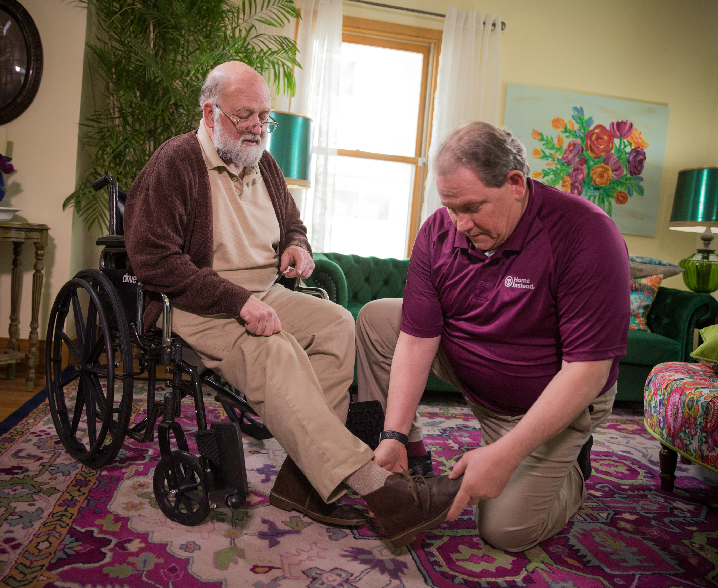 Caregiver helping senior in a wheelchair put on his shoes